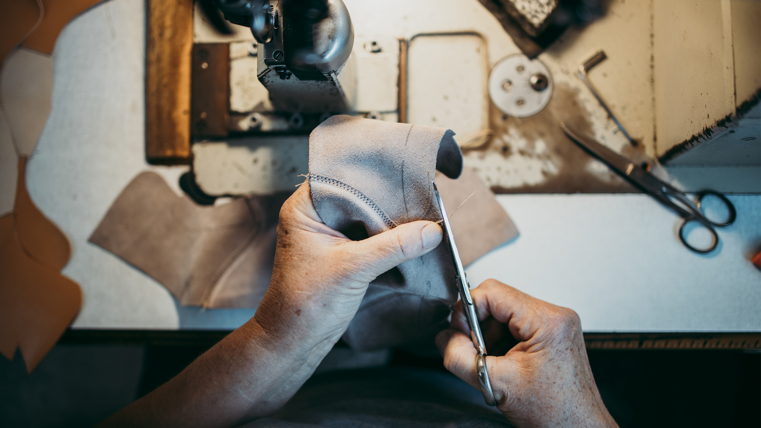 person cutting thread after stitching the shoe